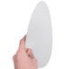 A hand holding a white board lid for a round foil take-out pan.