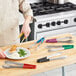 A person holding a pair of Choice stainless steel tongs with HACCP color coated handles.
