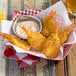 A bowl of fried Mrs. Friday's U/10 Size breaded fantail shrimp with sauce.