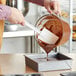 A person using a Choice white spatula to pour chocolate into a pan.