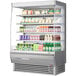 A Turbo Air stainless steel vertical open display case filled with drinks and beverages.