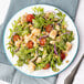 A plate of King & Prince Lobster Sensations Seafood Blend salad with tomatoes and nuts with a fork and knife on the table.