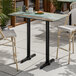 A rectangular bar height table with a textured canyon painted faux metal finish and black end base plates.
