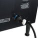 A black Grindmaster beverage dispenser with black and white hoses attached to a white pipe.