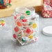 A 64 oz. Square PET plastic jar filled with lollipops and candies with a white lid.