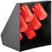 A black metal flatware organizer with red perforated cylinders.