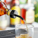 A Choice black free flow whiskey pourer attached to a bottle pouring liquid into a glass.