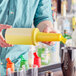 A person pouring liquid from a yellow Choice plastic container into a cup.