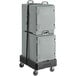 A grey plastic CaterGator pan carrier on a black cart with wheels and a strap.