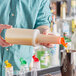 A person pouring liquid from a Choice plastic bottle with an orange flip top into a cup.