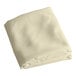 An ivory hemmed square table cover folded on a white background.