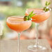 Two glasses of guava cocktails with straws and garnish.