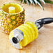 A pineapple sliced by an OXO Good Grips stainless steel pineapple corer.