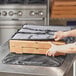 A person putting a pizza box into a gray Choice insulated pizza delivery bag.