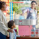 A woman and child using a Carnival King cotton candy machine with a floss bubble.