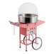 A pink cotton candy machine with a stainless steel bowl, clear dome cover, and wheeled cart.