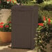 A brown Suncast outdoor waste container in a garden.