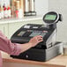 A person using a Royal Alpha cash register on a counter.