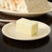 A block of butter on a tan Carlisle bread and butter plate.