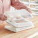 A person holding a Choice aluminum sheet pan with cookies in a plastic container.