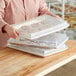 A woman holding a Choice half size aluminum sheet pan with cookies in it.