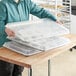 A woman holding a Choice wire rim aluminum sheet pan with cookies.