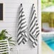 Two Monarch Brands gray striped pool towels hanging on a wall.