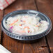 A Solo plastic sauce container with food inside on a table.