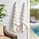 Two Monarch Brands beige striped pool towels hanging on a wall.