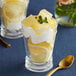 A glass of lemon fruit dessert with a spoon in it.
