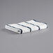 A white and navy blue striped Monarch Brands pool towel.