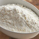 A bowl of meringue powder on a wooden table.