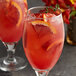 Two glasses of red liquid with Les Vergers Boiron blood orange garnish.