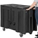 A person pushing a large black rectangular IRP Arctic Cooler.