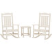 A group of white POLYWOOD rocking chairs with a white table with a square top.