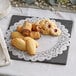 A table with a white Lace Normandy doily under a plate of cookies.