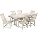 A POLYWOOD sand table with a white top and six chairs on a patio.