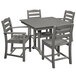 A POLYWOOD La Casa Cafe farmhouse dining table in slate grey with four chairs on an outdoor patio.