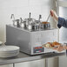 A woman holding a plate of food in front of a ServIt countertop food warmer.