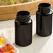 Two dark amber 100cc glass packer bottles on a counter next to a plate of jelly candies.