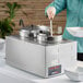 A woman using a ServIt countertop food warmer to pour soup into a bowl.