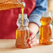 A person pouring honey into a Bear PET honey bottle.
