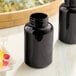 Two dark amber 300cc glass packer bottles with black caps on a counter next to a bowl of jelly beans.