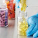 A hand pouring yellow pills into a 150cc clear packer bottle.