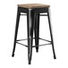 A black metal Lancaster Table & Seating backless counter height stool with a gray wood seat.