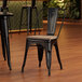 A Lancaster Table & Seating black metal chair with a gray wood seat at a table in a restaurant.