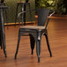 A Lancaster Table & Seating black metal arm chair with a gray wood seat.