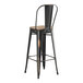 A black metal Lancaster Table & Seating bar stool with a gray wood seat.