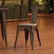 A Lancaster Table & Seating copper chair with a gray wood seat on a table in a coffee shop.