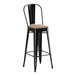 A Lancaster Table & Seating black metal bar stool with a gray wood seat.